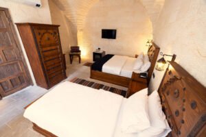 El oymalı masif ahşap yataklar, doğal taş kemerli mimari ve otantik dekorasyon detaylarıyla tasarlanmış butik otel odası interior görünümü