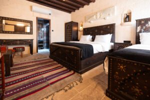 El işlemeli masif ahşap yatak takımı ve doğal taş detaylarla dekore edilmiş etnik butik otel odası interior tasarımı