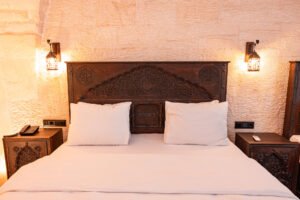El oymalı masif ahşap yatak başlığı ve doğal taş duvar detaylarıyla tasarlanmış otantik butik otel yatak odası dekorasyonu