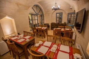El oymalı masif ahşap masa ve sandalyelerle dekore edilmiş Kapadokya tarzı butik otel restoran alanı interior tasarımı