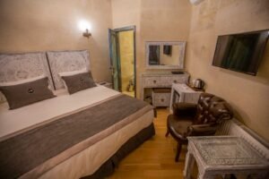 El oymalı beyaz masif ahşap mobilyalar ve etnik dekorasyon detaylarıyla tasarlanmış şık butik otel odası interior görünümü