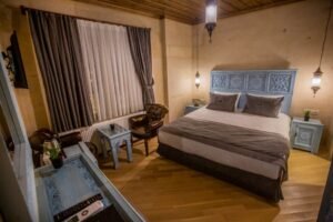 El oymalı masif ahşap yatak başlığı ve etnik dekorasyon detaylarına sahip şık butik otel odası tasarımı