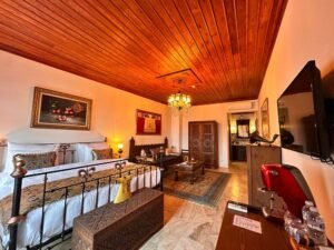 Masif ahşap işlemeli yatak, oymalı gardırop, etnik oturma alanı ve sıcak aydınlatmalı butik otel odası dekorasyonu interior tasarımı